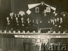 1933, Buenos Aires, Argentyna.
Marszałek Sejmu RP Władysław Raczkiewicz przemawia podczas spotkania z Polonią argentyńską. Na scenie również: p. Bernstein (siedzi 2. z lewej), p. Ciapciak (siedzi 3. z lewej), p. Jahilnicki (siedzi 2. z prawej), Stanisław Pyzik (siedzi 1. z lewej), prezes Związku Polaków w Argentynie Franciszek Marus (siedzi 4. z lewej),  p. Pikulski (siedzi w głębi. 2. z lewej od W. Raczkiewicza), prezes organizacji polonijnej w Dock Sud p. Pleśniak (siedzi w głębi. 1. z lewej od W. Raczkiewicza),  Juliusz Nowiński z Banco Polaco (siedzi 1. z prawej), Rudolf Friedenberg (siedzi 3. z prawej), Zygmunt Zach (siedzi 4. z prawej), p. Prochownik (siedzi 5. z prawej). Na dole sceny zawieszono hasło: 