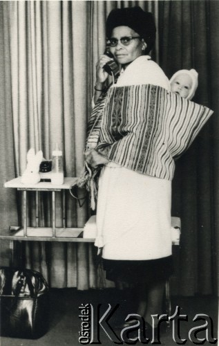 1975, Afryka.  
Kobieta z dzieckiem na plecach rozmawiająca przez telefon. 
Fot. NN, kolekcja Ireny Wolickiej-Wolszleger, reprodukcje cyfrowe w Ośrodku KARTA
