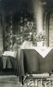 Lata 40., brak miejsca.
Kobieta prawdopodobnie zapala świeczki stojące przy stroiku na stole. 
Fot. NN, kolekcja: Polska Misja Katolicka, reprodukcje cyfrowe w Ośrodku KARTA
