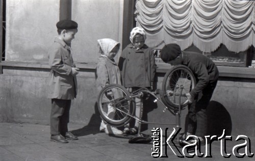 Lata 60., Warszawa, Polska.
Dzieci na ulicy naprawiają rower.
Fot. Marek Zürn, zbiory Fundacji Ośrodka KARTA