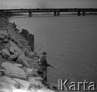 Lata 60., Warszawa, Polska.
Chłopiec wędkujący nad Wisłą, w głębi Most Gdański.
Fot. Marek Zürn, zbiory Fundacji Ośrodka KARTA