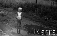 Lata 60., miejsce nieznane, Polska.
Dziecko wiejskie podczas zabawy na błotnistej drodze.
Fot. Marek Zürn, zbiory Fundacji Ośrodka KARTA