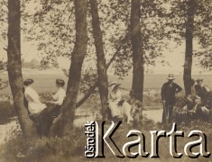 1900-1920, miejsce nieznane.
Portret grupowy wykonany na skarpie, nad rzeką. Ludzie siedzą miedzy drzewami. W tle widać drzewa, łąki, pola.
Fot. NN, kolekcja rodziny Walińskich, zbiory Fundacji Ośrodka KARTA