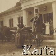 1900-1920, miejsce nieznane, Polska.
Mężczyzna stoi na drugim mężczyźnie. Wita się z trzecim mężczyzną. Stoją obok powozu konnego przed dworem. W powozie konnym siedzi woźnica. Przy wejściu do dworu inne osoby.
Fot. NN, kolekcja rodziny Walińskich, zbiory Fundacji Ośrodka KARTA