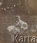 1920-1930, miejsce nieznane, Polska.
Dziewczynka z psem. Siedzą w trawie. W oddali drzewa.
Fot. NN, kolekcja rodziny Walińskich, zbiory Fundacji Ośrodka KARTA