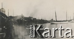1920-1930, miesjce nieznane.
Spotkanie w porcie. Cztery osoby stoją obok łódek i rozmawiają. W oddali widać budynki, łódki, morze.
Fot. NN, kolekcja rodziny Walińskich, zbiory Fundacji Ośrodka KARTA