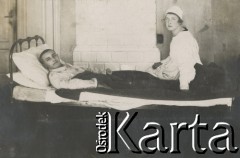 1920-1930, miejsce nieznane, Polska.
Pielęgniarka z pacjentem. Mężczyzna leży, kobieta siedzi na skraju łóżka.
Fot. NN, kolekcja rodziny Walińskich, zbiory Fundacji Ośrodka KARTA