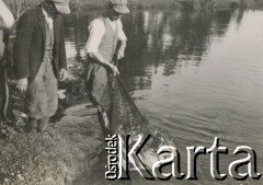 1930-1940, miejsce nieznane, Polska.
Łowienie ryb. Mężczyzna wyciąga pełną sieć z wody.
Fot. NN, kolekcja rodziny Walińskich, zbiory Fundacji Ośrodka KARTA