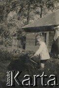 1930-1950, miejsce nieznane, Polska.
Dziecko z psem w ogrodzie. Dalej stoi kobieta.
Fot. NN, kolekcja rodziny Walińskich, zbiory Fundacji Ośrodka KARTA