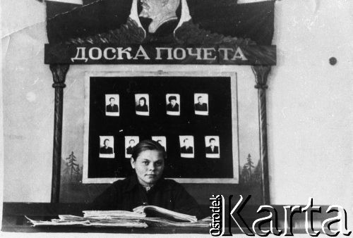 Brak daty, ZSRR.
Dziewczyna siedząca za stołem nad książką. Za nią tablica z fotografiami, profilem Lenina i napisem: 