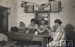 1937, Poleskie woj., Polska
Wnętrze poleskiej chaty, rodzina przy wieczerzy, na ścianie obrazy z Matką Boską; na odwrocie pieczątka zakładu: 