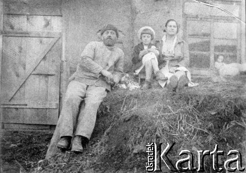 1944, Kiemierowska obł., ZSRR
Rodzina polska na zesłaniu. Rodzice z dzieckiem siedzą na kupie siana przed drewnianą chałupą - Elwira Adamczewska z matką i ojcem w kołchozie 