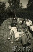 1940, Rumunia.
Polscy uchodźcy w Rumunii podczas II wojny światowej - grupa osób w letnich ubraniach siedzi na sianie, z przodu mężczyzna z dzieckiem na kolanach, na górze leży Tadeusz Krajewski.
Fot. NNH, zbiory Ośodka KARTA, udostępnił Adam Krajewski.