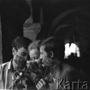 1968, Zamość, woj. lubelskie, Polska.
Kobieta i dwóch mężczyzn pozują do zdjęcia z różami. Z tyłu za nimi widoczne ciągnące się wzłuż kamienicy arkady.
Fot. Irena Jarosińska, zbiory Ośrodka KARTA
