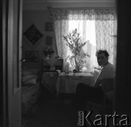 1950-1960, Nowa Huta, Kraków, Polska.
Wnętrze pokoju rodzinnego. Mężczyzna przy stole, z lewej strony radioodbiornik marki Etiuda.
Fot. Irena Jarosińska, zbiory Ośrodka KARTA. 




