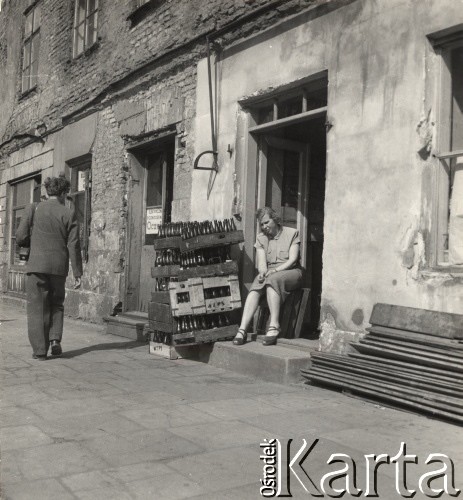 lata 50-te, Warszawa, Polska.
Kobieta siedząca na progu domu, obok niej stoją skrzynki z butelkami.
Fot. Irena Jarosińska, zbiory Ośrodka KARTA.
