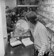 1968-1972, Kraków lub Rzeszów, Polska.
Dział kosmetyczny w sklepie Banku PeKaO. Kobieta maluje usta szminką.
Fot. Irena Jarosińska, zbiory Ośrodka KARTA