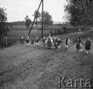 1961, Kadzidło, Polska.
Wieś kurpiowska. Wiejska droga. Kobieta w stroju kurpiowskim, za nią dzieci trzymające się za ręce.
Fot. Irena Jarosińska, zbiory Ośrodka KARTA