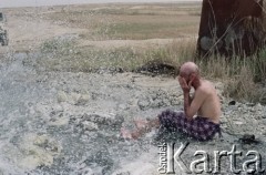 1992, Kabul, prowincja Kabul, Afganistan.
Konwój podczas postoju w obozowisku. Na zdjęciu mężczyzna bierze kąpiel korzystając z zaimprowizowanego natrysku przy hydrancie. 
Fot. Irena Jarosińska, zbiory Ośrodka KARTA
