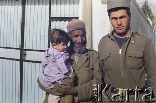 1992, Kabul, prowincja Kabul, Afganistan.
Mężczyzna ubrany w stary wojskowy mundur trzyma na rękach dziewczynkę. Obok niego stoi żołnierz.
Fot. Irena Jarosińska, zbiory Ośrodka KARTA