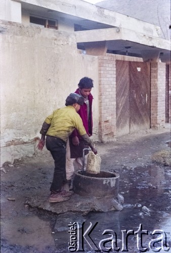 1992, Kabul, prowincja Kabul, Afganistan.
Chłopcy nabierają do kanistra wodę z ulicznej studzienki.
Fot. Irena Jarosińska, zbiory Ośrodka KARTA