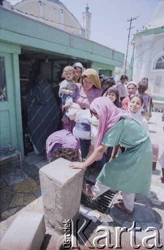 1992, Kabul, prowincja Kabul, Afganistan.
Grupa kobiet i dzieci nieopodal meczetu Shah-Do Shamshira (Meczet Króla Dwóch Mieczy), świątyni wzniesionej w 1920 roku za panowania króla Amanullaha. Kobiety obmywają stopy wodą z ulicznego kraniku.
Fot. Irena Jarosińska, zbiory Ośrodka KARTA