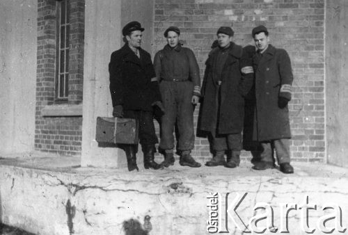 Wiosna 1944, Wierzbałowo (Virbalis), Litwa.
Chłopcy wywiezieni w kwietniu 1943 z okolic Wilna do pracy przymusowej na dużej przygranicznej stacji kolejowej w Kybartach (Kybartai). Stacja nosiła nazwę starszej od miasteczka Kybarty wsi Wierzbałowo odległej o 5 km. Przy wieży ciśnień, niedaleko warsztatów parowozowych, stoją od lewej: NN (starszy od pozostałych mechanik parowozowy, wilnianin), w kombinezonie Sienkiewicz, w płaszczach Misiun i Michał Janowicz, niebieskie opaski z napisem 