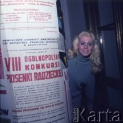 Listopad 1970, prawdopodobnie Kozienice, Polska.
Kobieta przy plakacie reklamującym  VIII Konkurs Piosenki Radzieckiej. 
Fot. Romuald Broniarek, zbiory Ośrodka KARTA.