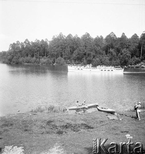 Lipiec 1956, Mazury, Polska.
Statek wycieczkowy płynący wzdłuż brzegu jeziora, na pierwszym planie turyści w kajaku.
Fot. Romuald Broniarek, zbiory Ośrodka KARTA