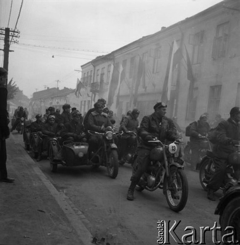 26-30.09.1956, Polska.
Uczestnicy motocyklowego rajdu TPPR Warszawa-Poronin przejeżdżają ulicą miasta udekorowaną biało-czerwonymi flagami.
Fot. Romuald Broniarek, zbiory Ośrodka KARTA