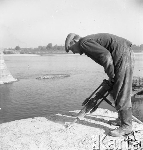 Wrzesień 1957, Warszawa, Polska.
Budowa Mostu Gdańskiego na filarach i z wykorzystaniem niektórych elementów konstrukcyjnych zburzonego Mostu przy Cytadeli. Robotnik ze świdrem.
Fot. Romuald Broniarek, zbiory Ośrodka KARTA