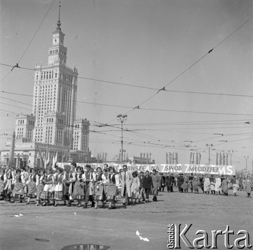 1.05.1958, Warszawa, Polska. 
Obchody święta 1 Maja, uczestnicy pochodu - grupa osób w strojach ludowych oraz członkowie Związku Młodzieży Socjalistycznej z transparentem.
Fot. Romuald Broniarek, zbiory Ośrodka KARTA