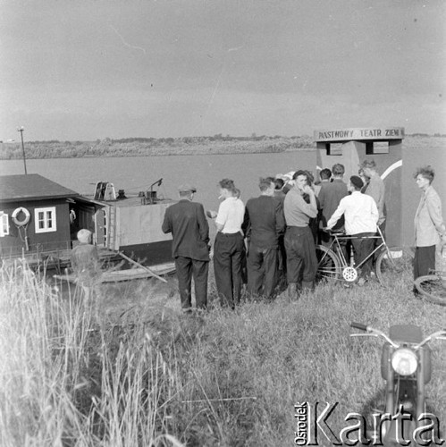 Lipiec 1958, Polska.
Teatr Ziemi Mazowieckiej podczas tournée na barce płynącej z biegiem Wisły - mieszkańcy wsi kupują bilety w kasie stojącej na brzegu.
Fot. Romuald Broniarek, zbiory Ośrodka KARTA