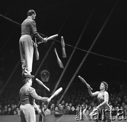 Kwiecień 1959, Warszawa, Polska. 
Występ cyrku ze Szwecji, artyści cyrkowi żonglujący maczugami, jeden mężczyzna stoi na głowie drugiego, w tle publiczność.
Fot. Romuald Broniarek, zbiory Ośrodka KARTA