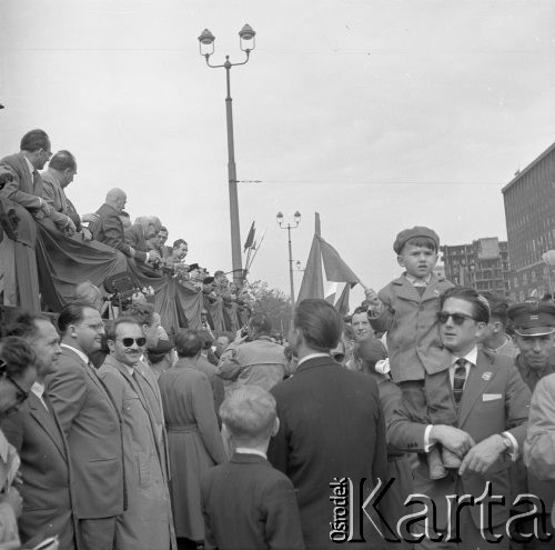 1.05.1959, Warszawa, Polska. 
Obchody święta 1 Maja, pochód ulicą Marszałkowską, uczestnicy niosą flagi PRL i ZSRR, po lewej fragment trybuny honorowej i zwróceni w jej kierunku dziennikarze. Na trybunie trzeci od lewej stoi premier Józef Cyrankiewicz, za nim kolejno: I sekretarz KC PZPR Władysław Gomułka, przewodniczący Rady Państwa Aleksander Zawadzki.
Fot. Romuald Broniarek, zbiory Ośrodka KARTA