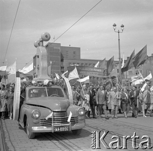 1.05.1959, Warszawa, Polska. 
Obchody święta 1 Maja, pochód ulicą Marszałkowską, na pierwszym planie samochód marki Warszawa FSO wiezie imadło, za nim tłum niesie flagi PRL i ZSRR oraz transparent z hasłem propagandowym: 