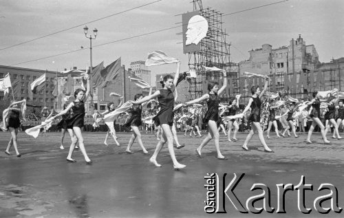 1.05.1959, Warszawa, Polska. 
Obchody święta 1 Maja, pochód przechodzący ulicą Marszałkowską, na pierwszym planie dziewczęta machające kawałkami białego materiału, w tle powiewają flagi PRL i ZSRR, tłum obserwatorów, nad nimi portret Włodzimierza Lenina i hasło propagandowe: 