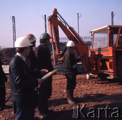 Marzec 1975, Dąbrowa Górnicza, woj. Katowice, Polska.
Budowa Huty Katowice, grupa robotników w kaskach i kombinezonach roboczych na placu budowy.
Fot. Romuald Broniarek/KARTA