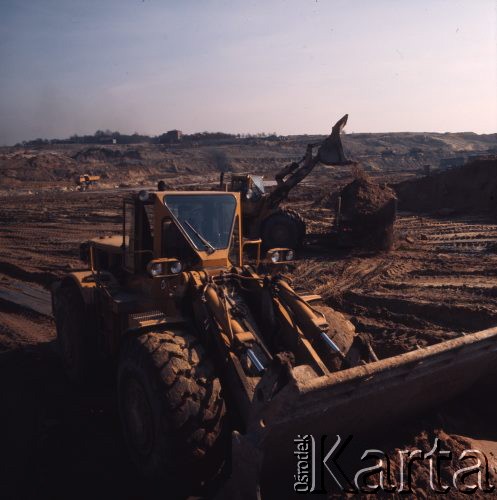 Marzec 1975, Dąbrowa Górnicza, woj. Katowice, Polska.
Budowa Huty Katowice, spychacze przy pracy, ładowanie ziemi na ciężarówkę.
Fot. Romuald Broniarek/KARTA
