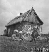 Lipiec 1956, Czarnolas (okolice), Polska.
Troje dzieci na tle chaty krytej strzechą.
Fot. Romuald Broniarek, zbiory Ośrodka KARTA