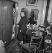 Październik 1958, Warszawa, Polska.
Kobieta w czarnej sukience stoi obok szafy, na pierwszym planie krzesło i okrągły stolik.
Fot. Romuald Broniarek, zbiory Ośrodka KARTA