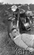 Kwiecień 1959, Polska. 
Kobieta w okularach przeciwsłonecznych i chustce na głowie leżąca na trawie obok motocykla.
Fot. Romuald Broniarek, zbiory Ośrodka KARTA
