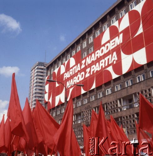 1.05.1975, Warszawa, Polska. 
Obchody święta 1 Maja, manifestanci z czerwonymi flagami, hasło na ścianie budynku: 