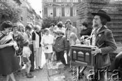 Sierpień 1976, Warszawa, Polska.
Kataryniarz na Barbakanie, obok niego grupa turystów.
Fot. Romuald Broniarek/KARTA