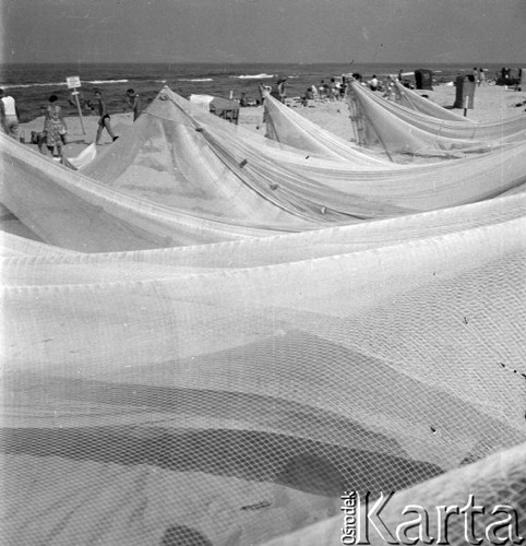 Lipiec 1959, Jastarnia, Polska.
Wypoczynek nad Bałtykiem - wczasowicze na plaży. Na pierwszym planie suszą się sieci rybackie.
Fot. Romuald Broniarek/KARTA