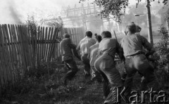 Sierpień 1959, Sandomierz, Polska.
Płonący budynek, na pierwszym planie mężczyźni biorący udział w akcji ratunkowej niszczą płot, żeby zapobiec rozprzestrzenianiu się pożaru.
Fot. Romuald Broniarek/KARTA
