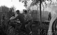 Sierpień 1959, Sandomierz, Polska.
Płonący budynek, na pierwszym planie mężczyźni biorący udział w akcji ratunkowej niszczą płot, żeby zapobiec rozprzestrzenianiu się pożaru.
Fot. Romuald Broniarek/KARTA