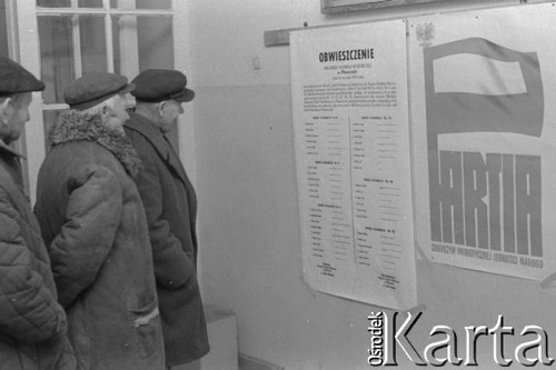 Styczeń 1978, Jazgarzew k/Warszawy, Polska.
Spotkanie przed wyborami do gminnych Rad Narodowych, trzej mężczyźni czytający obwieszczenie. Z prawej wisi plakat: 