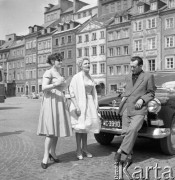 Maj 1960, Warszawa, Polska.
Dwie kobiety i mężczyzna na Rynku Starego Miasta, w tle kamienice wschodniej pierzei. Mężczyzna opiera się o maskę samochodu marki 