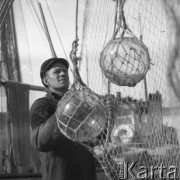 Czerwiec 1962, Władysławowo, Polska.
Rybak na pokładzie kutra, na pierwszym planie sieć i boje rybackie.
Fot. Romuald Broniarek/KARTA